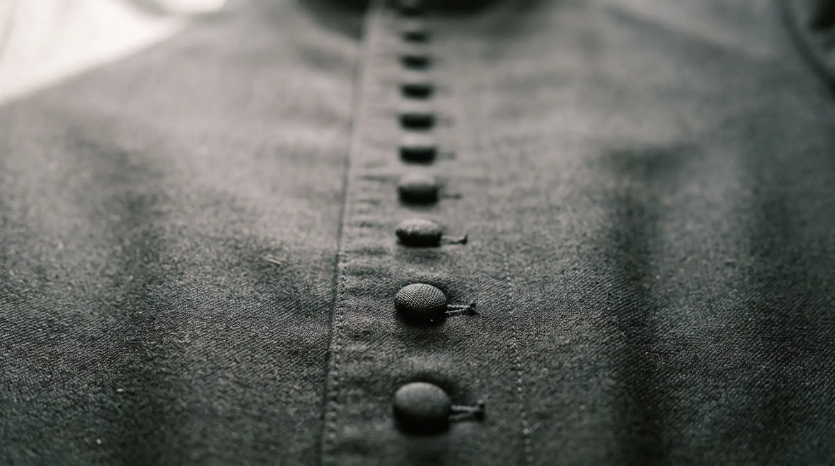 Close-up of the cloth-covered buttons running down the front placket of a black wool cassock