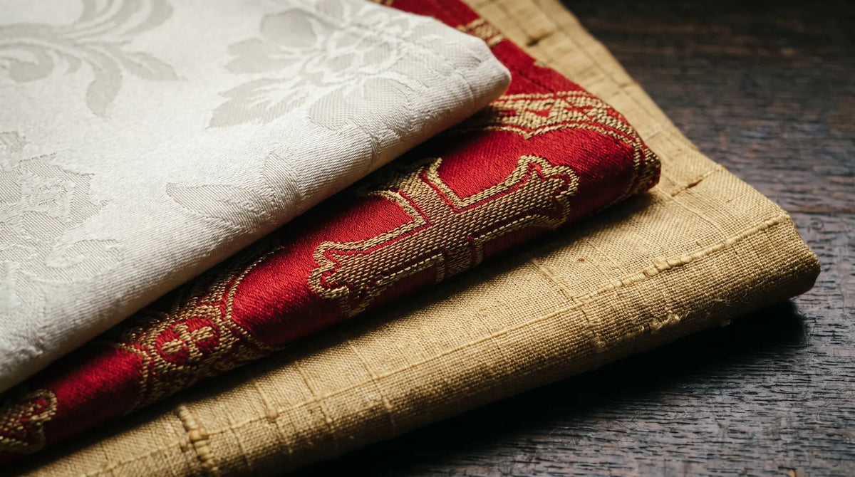 Macro detail of ivory damask, red brocade with metallic weft and slubbed golden dupioni silk overlapping