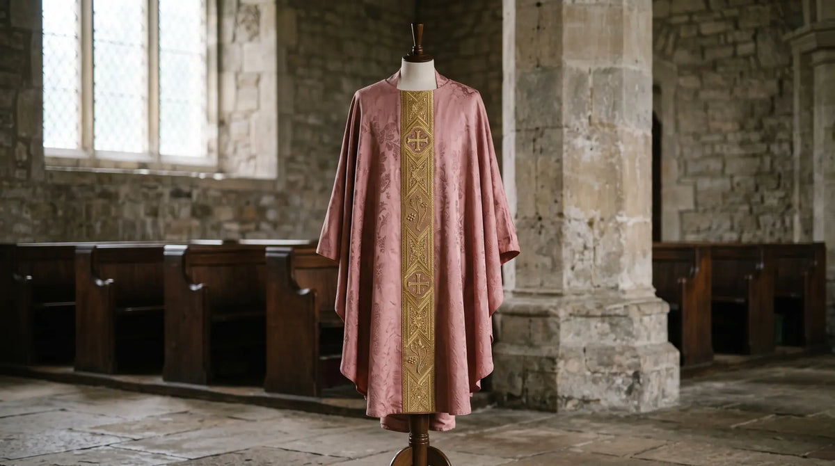 A dusty rose silk damask chasuble with a gold orphrey on a dress form in a quiet stone church