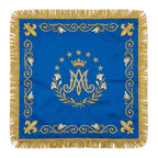 Marian blue chalice veil laid flat, showing the crowned Ave Maria monogram in a wreath of lilies with fleur-de-lis at the corners.