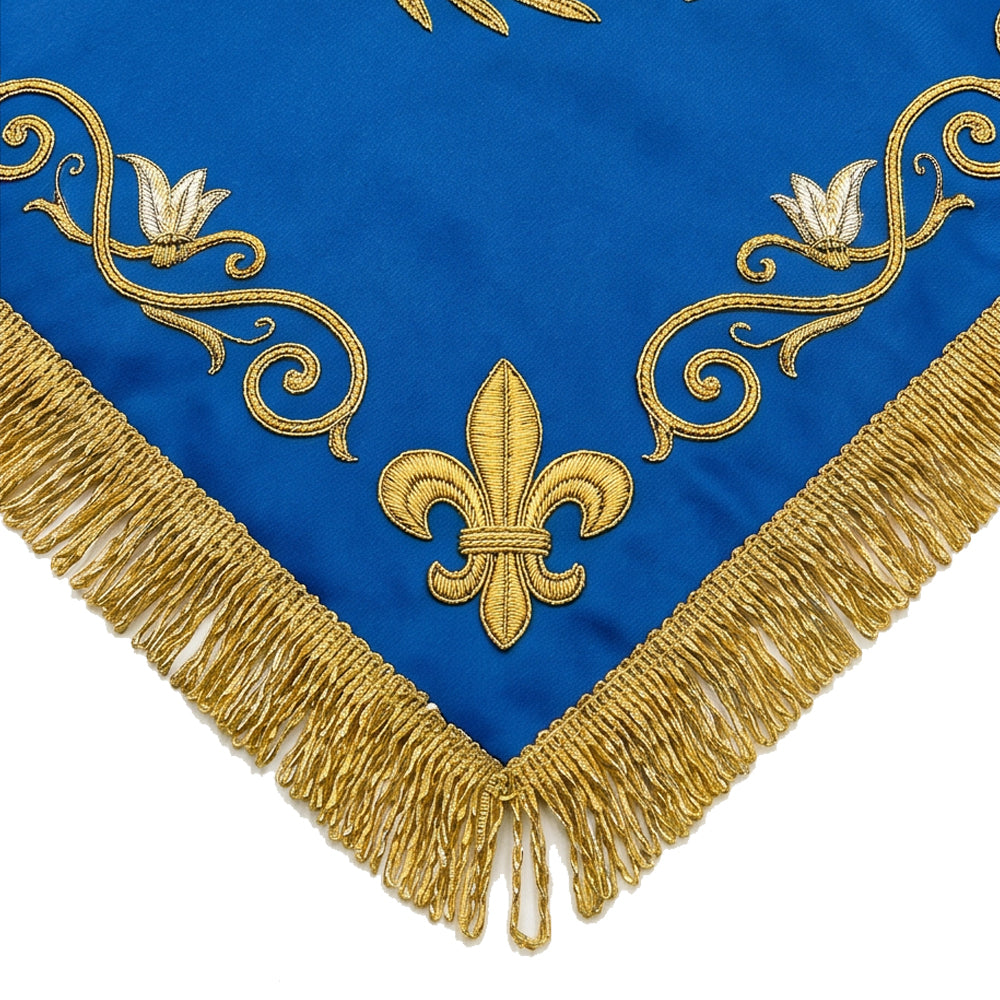 Close-up of the Marian blue chalice veil's corner, showing the gold fleur-de-lis, lily and scrollwork above the bullion fringe.