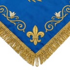 Close-up of the Marian blue chalice veil's corner, showing the gold fleur-de-lis, lily and scrollwork above the bullion fringe.