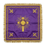 Purple chalice veil laid flat, showing the gold cross ringed by the crown of thorns in rays, with a crossed emblem at each corner.