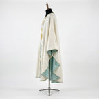 Side view of the ivory baptism chasuble showing the gothic drape and the aqua satin lining at the sleeve