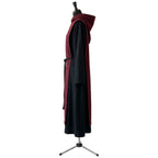 Side profile of a black and burgundy monk habit showing the standing hood and bell sleeve.