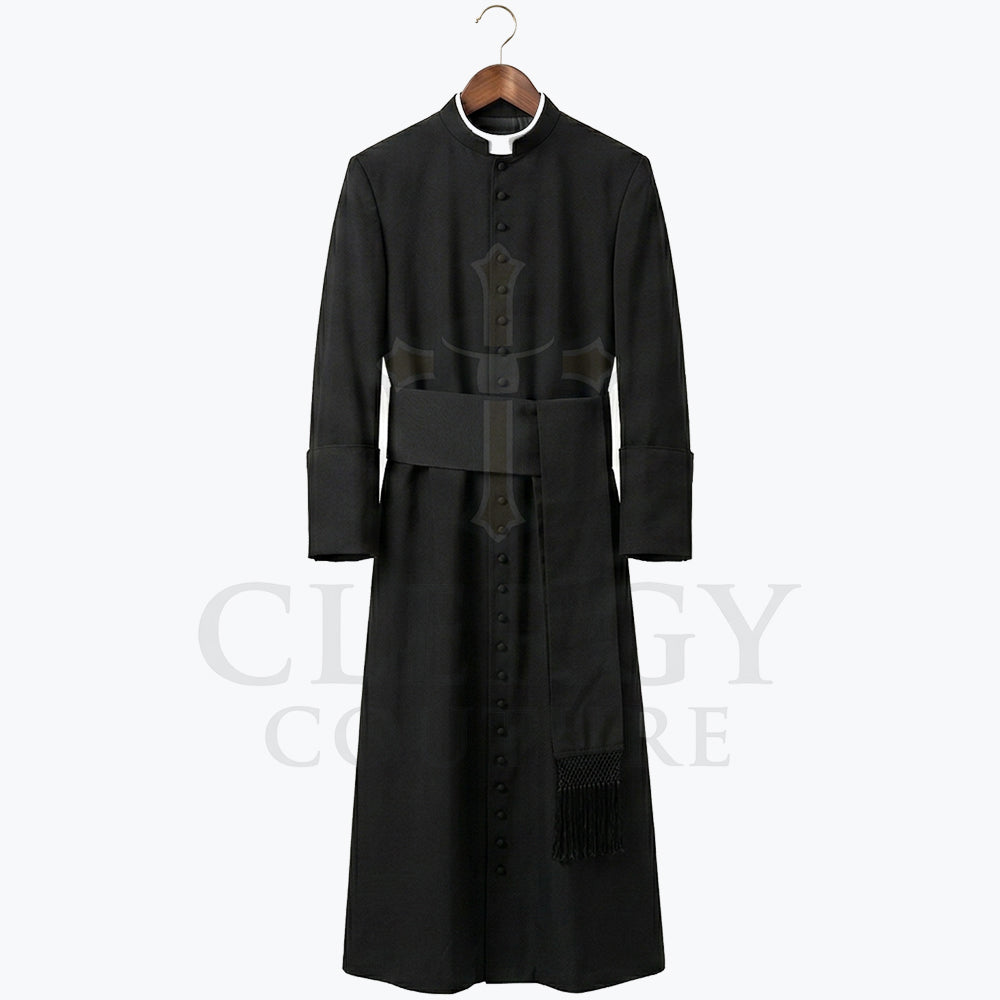 Front view of a black clergy cassock robe on a hanger, showing the stand collar and the wide sash belt with hanging tassel.