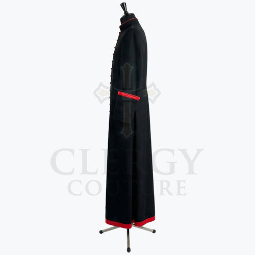 Side view of the black cassock robe showing the red cuff band and the red band at the hem.
