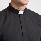 Close-up of the tall black tab collar with a white tab, the covered button placket and the top of the chest pocket.