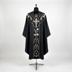 Back of the black requiem chasuble with a Y-shaped velvet orphrey: radiant cross, palms, white lilies, gothic arches with crosses and an anchor at the hem