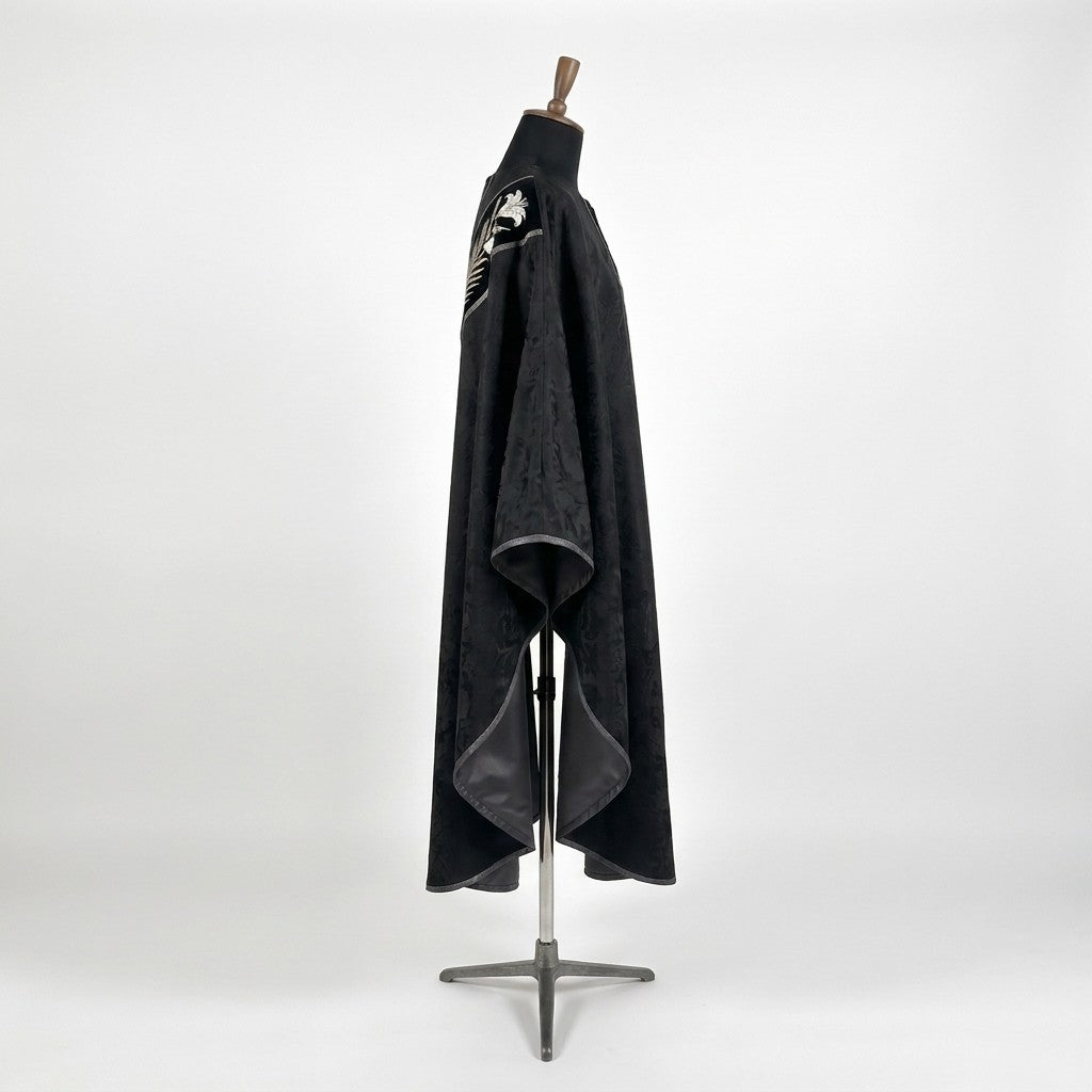 Side view of the black chasuble showing the damask pattern, gothic drape and grey satin lining