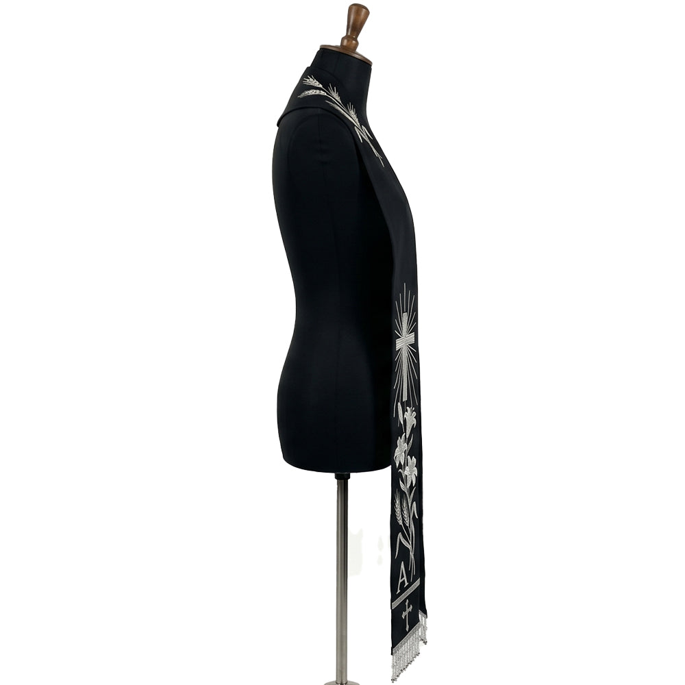 Close side view of the black stole's silver wheat, cross, lily and Alpha letter embroidery above beaded fringe