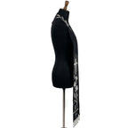 Close side view of the black stole's silver wheat, cross, lily and Alpha letter embroidery above beaded fringe