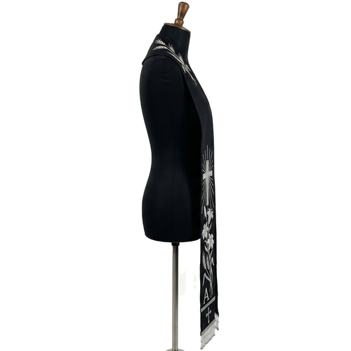 Close side view of the black stole's silver wheat, cross, lily and Alpha letter embroidery above beaded fringe