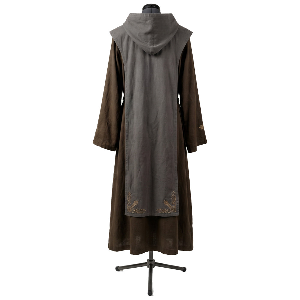 Back view of a brown hooded habit showing the grey scapular's gold cross embroidery near the hem.