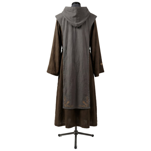 Back view of a brown hooded habit showing the grey scapular's gold cross embroidery near the hem.