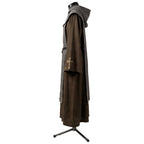 Side profile of a brown monk habit showing the gold cross motif embroidered on the sleeve cuff.