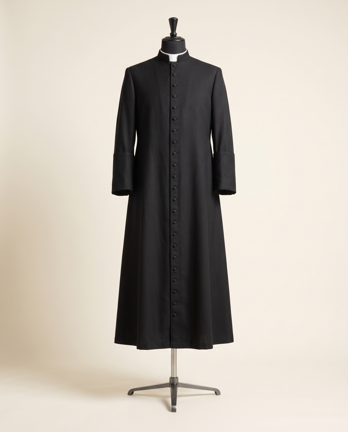 A tailored black wool Roman cassock with a full row of buttons and a white clergy tab collar, shown on a tailor's dress form