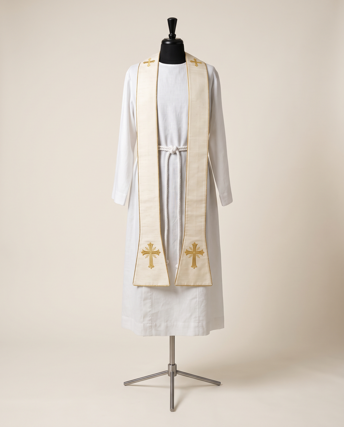 An ivory and gold embroidered priest stole hanging over the shoulders of a white linen alb on a tailor's dress form