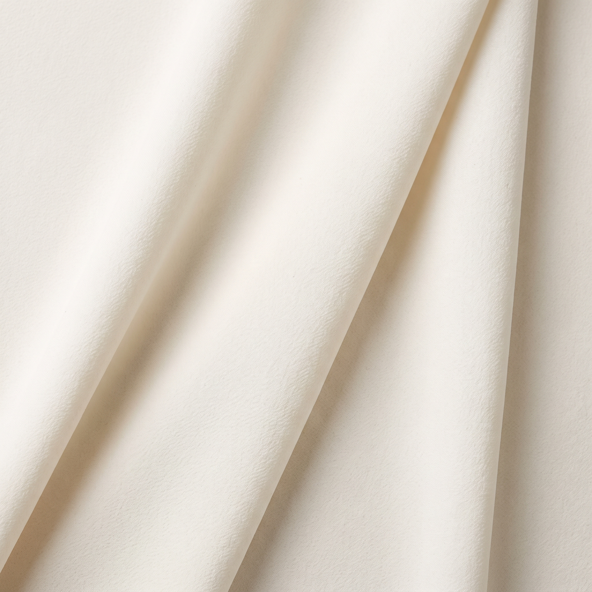 Ivory polyester crepe with a fine pebbled surface falling in soft folds