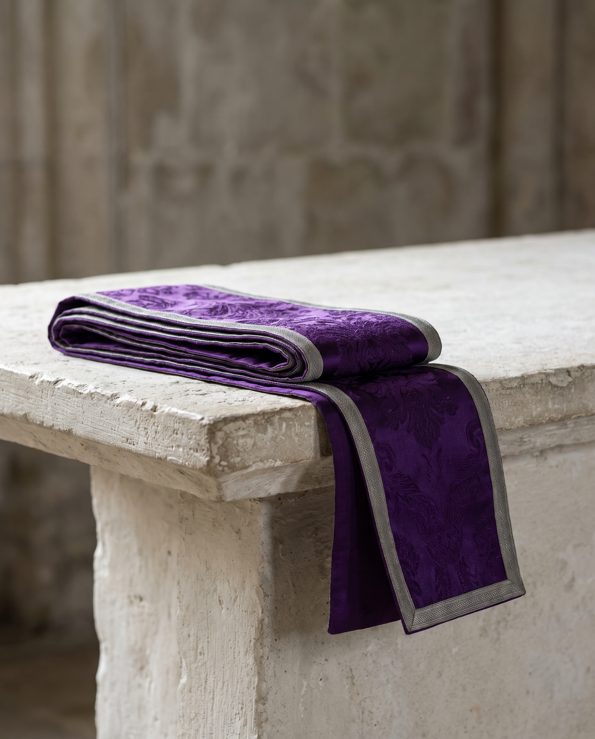 A folded violet stole with restrained silver-grey edging