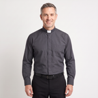 Man wearing the charcoal long-sleeve tab-collar clergy shirt with a white tab (shown for styling, not included), covered placket and left chest pocket, against a light grey background.