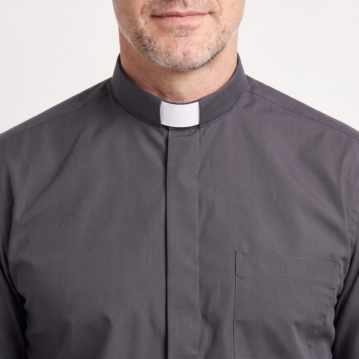 Close-up of the tall charcoal tab collar with a white tab, the covered button placket and the top of the chest pocket.