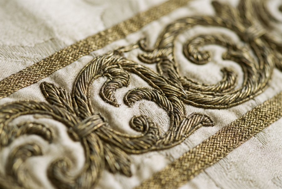Macro detail of laid goldwork thread couched onto ivory silk damask along an orphrey band