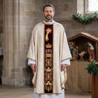 A priest wearing the ivory Epiphany chasuble with burgundy velvet orphrey beside a Nativity crib in a stone church