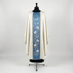 Front of an ivory damask chasuble with a Marian blue column orphrey: a silver crescent moon ringed by twelve stars above a vine of white lilies