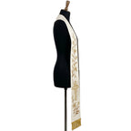 Close view of one ivory stole panel, showing the gold lily vine, the Alpha letter and gold beaded fringe at the hem.
