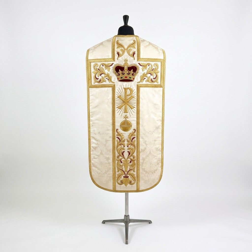 Back of the ivory fiddleback chasuble with a gold cross orphrey: crimson velvet royal crown at the crossing, radiant Chi Rho, orb and cross, and acanthus scroll