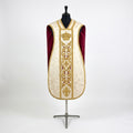 Front of an ivory damask fiddleback chasuble with a gold column orphrey: a crown, acanthus scrolls and a fleur-de-lys, showing the crimson lining at the sides