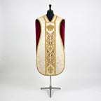 Front of an ivory damask fiddleback chasuble with a gold column orphrey: a crown, acanthus scrolls and a fleur-de-lys, showing the crimson lining at the sides
