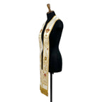 Close view of one panel on the ivory stole, showing the crown, cross, IHS monogram and crossed torches in gold thread.