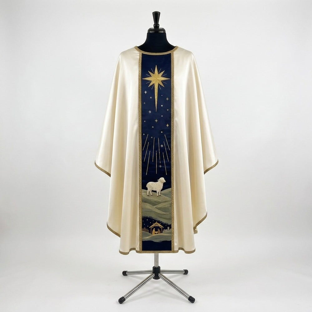 Front of an ivory satin Nativity chasuble with a navy column orphrey: a gold star with long rays above a white lamb on green hills and the stable at the hem