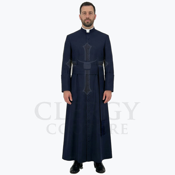 A pastor wearing the navy blue clergy cassock robe, front view, showing the stand collar and the sash belt with tassel.