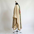 Side view of the ivory Guadalupe chasuble showing the floral damask, gothic drape and gold-trimmed sleeve