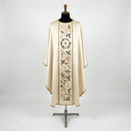 Front of an ivory satin Christmas chasuble with a column orphrey of a holly wreath round a gold star, blush poinsettias, holly and red berries