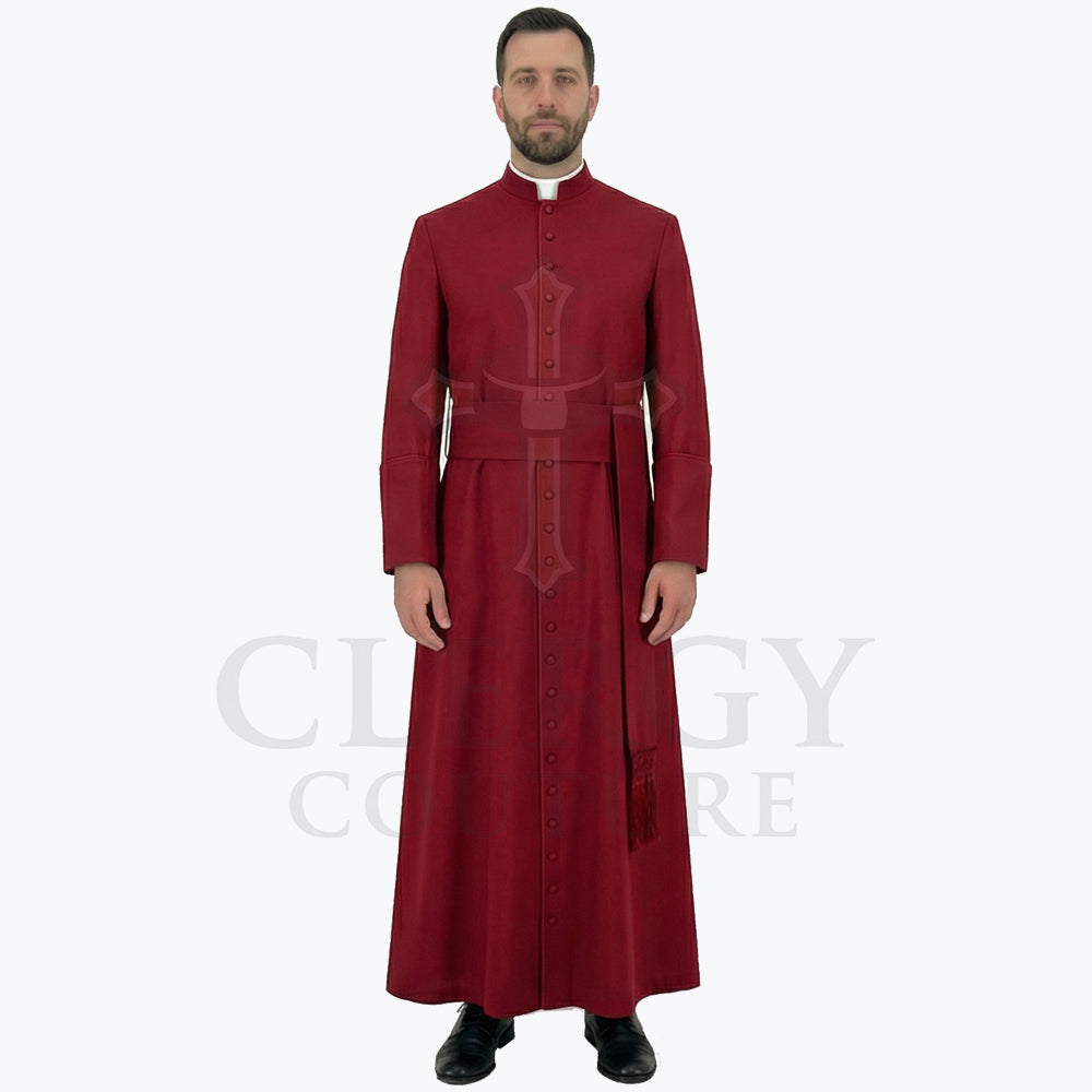 A minister wearing the deep red clergy cassock robe, front view, showing the stand collar and the sash belt with tassel.