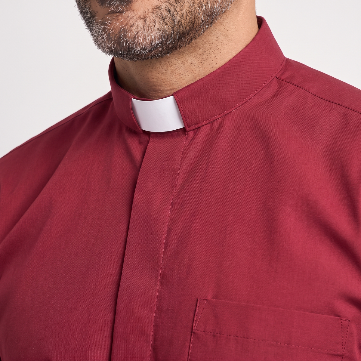 Close-up of the tall red tab collar with a white tab, the covered button placket and the top of the chest pocket.