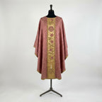 Front of a rose damask chasuble with a gold column orphrey: a heraldic rose bearing a cross, a climbing rose vine and a lit candle at the hem