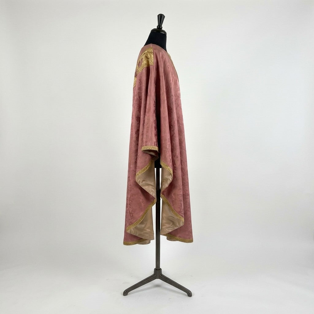 Side view of the rose damask chasuble showing the gothic drape, gold trim and champagne lining