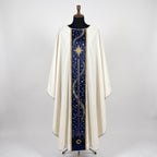 Front of an ivory chasuble with a navy column orphrey: a gold eight-pointed star, constellations, a silver trail of light and the Bethlehem skyline with the stable at the hem