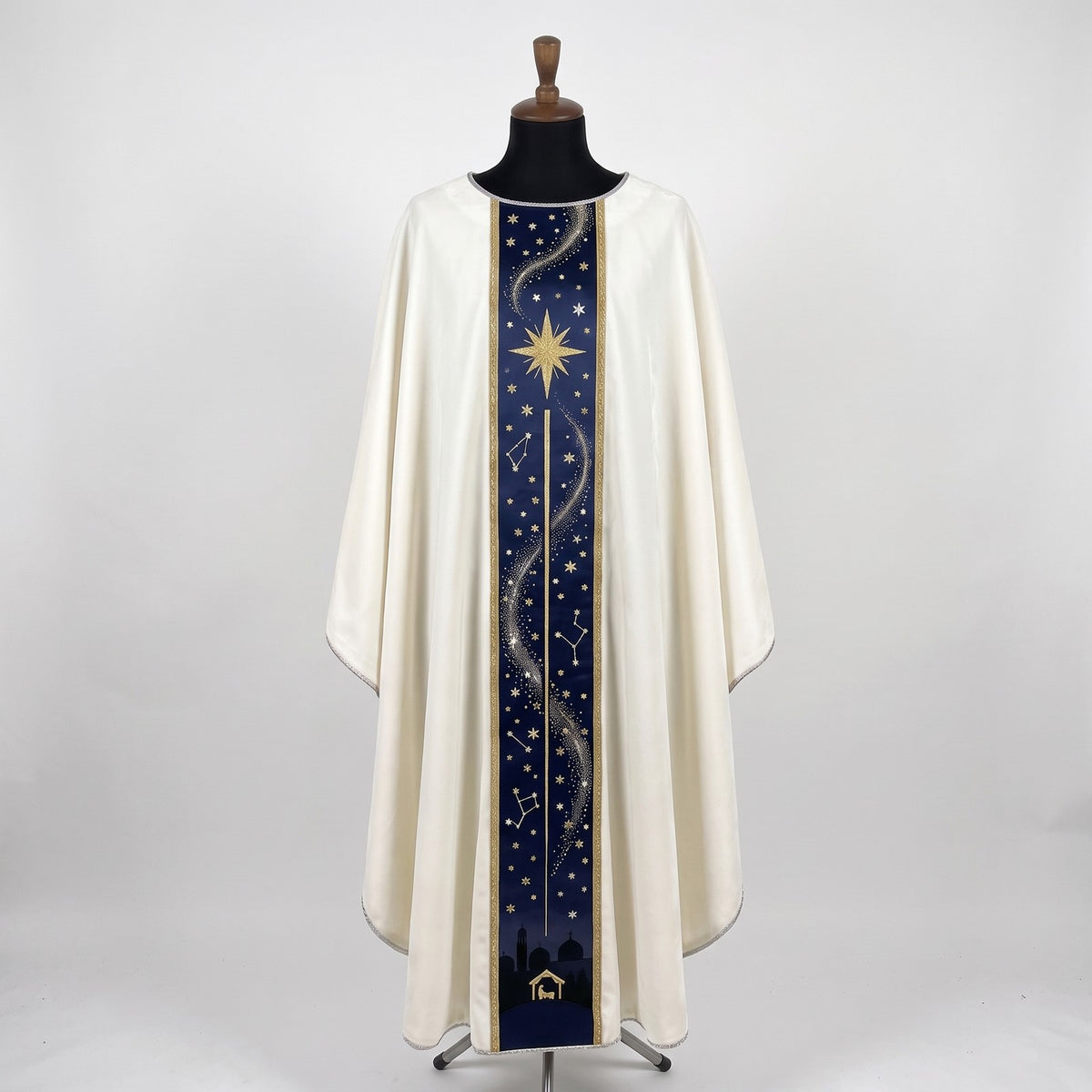 Front of an ivory chasuble with a navy column orphrey: a gold eight-pointed star, constellations, a silver trail of light and the Bethlehem skyline with the stable at the hem