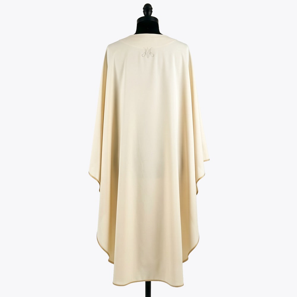 Plain ivory back of the chasuble with a small tone-on-tone Marian monogram at the neck and gold piping at the hem